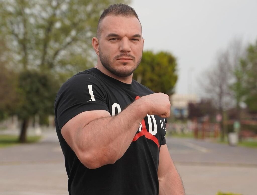 Ermes Gasparini flexing his bicep, showcasing his strength as he prepares for his next big arm wrestling supermatch in January 2024.